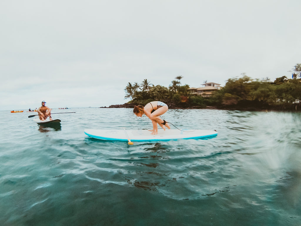 Attempting SUP yoga on a stand up paddle boarding tour with Maui SUP
